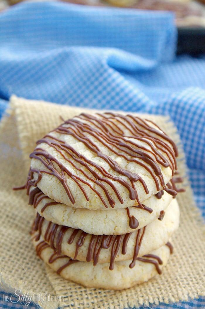 Close up of stacked cookies on burlap showing chocolate drizzle.