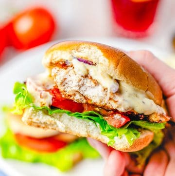 Hand holding up sandwich with bite taken out