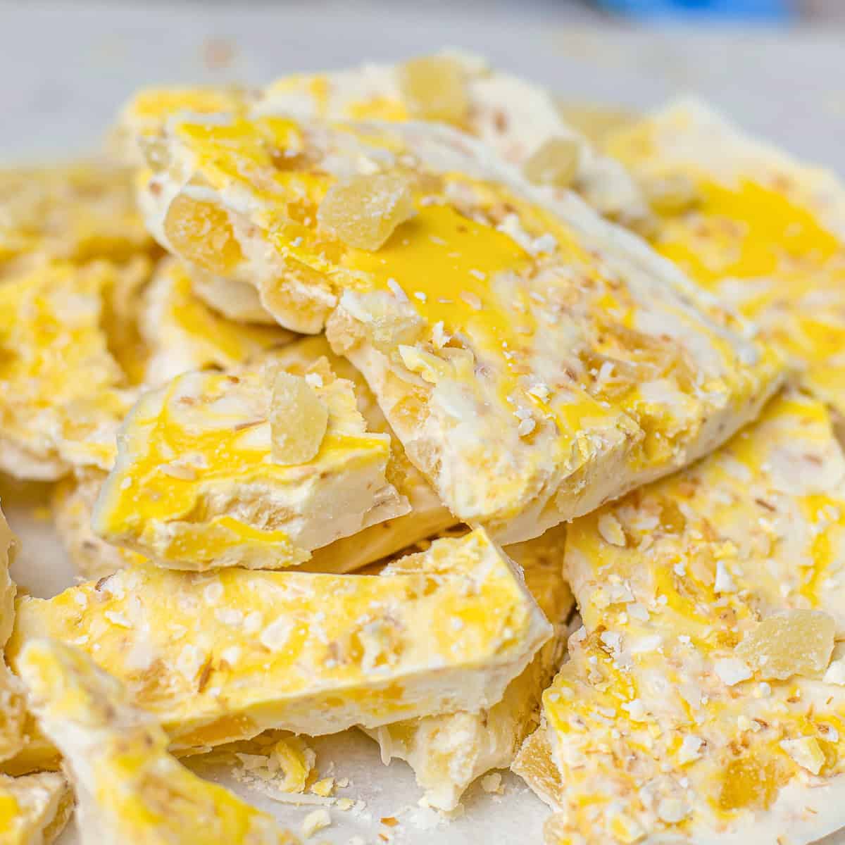 Chunks of pina colada bark with dried pineapple, toasted coconut, and yellow candy melt swirls.