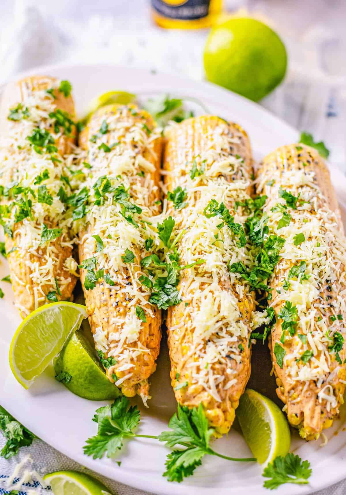 Side view of plated corn on platter garnished with limes and cilantro