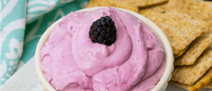Close up of swirled blackberry marshmallow dip showing the creamy whipped texture with a blackberry on top.