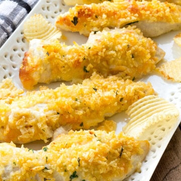 Baked potato chip chicken tenders with a golden crushed chip crust arranged on a white platter.