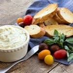 Whipped Goat Cheese Bruschetta spread in a bowl with toasted baguette slices, tomatoes, and fresh basil.