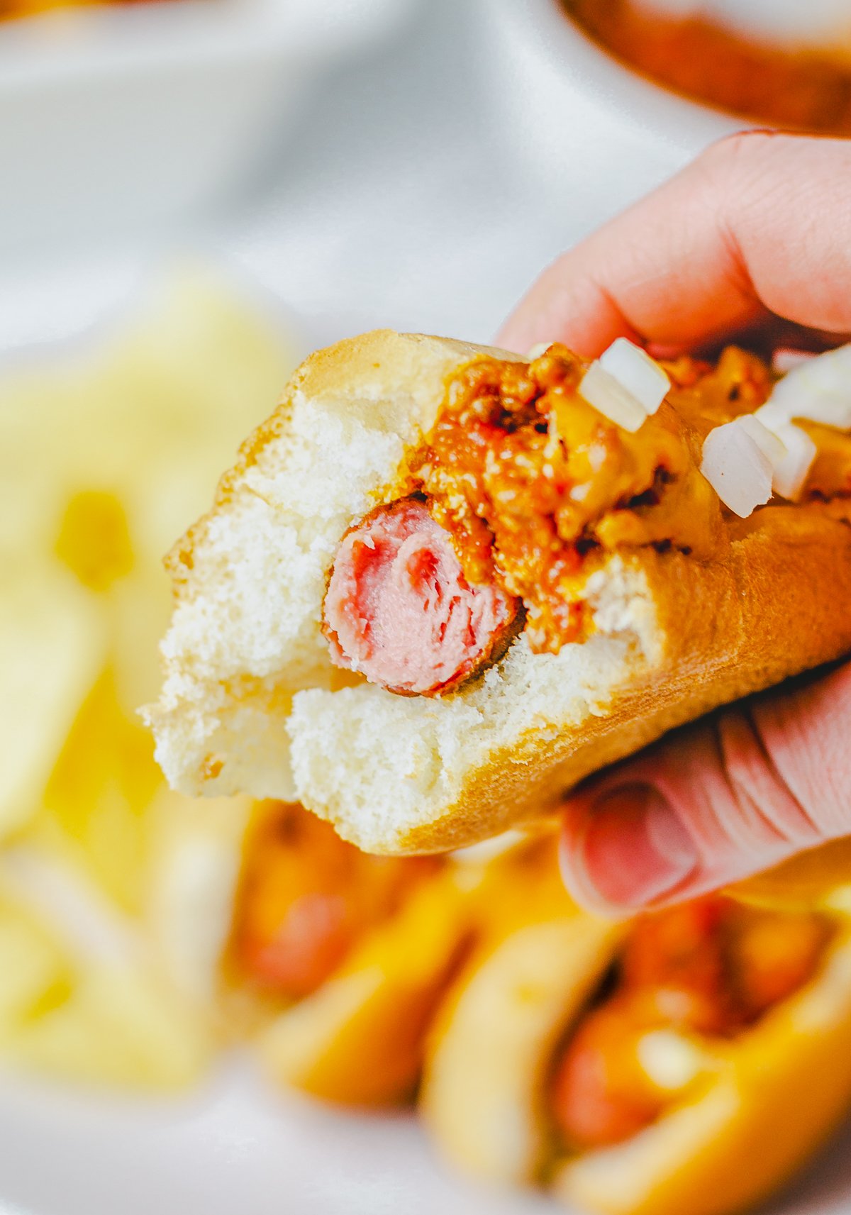 Bite taken out of hot dog being held by hand