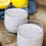Two glasses of creamy lemon blueberry smoothie topped with fresh blueberries.