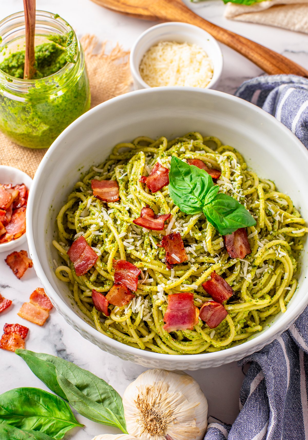 Overhead of Bacon Pesto Pasta in serving bowl topped with bacon and basil.