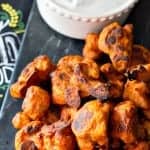 A platter of crispy buffalo cauliflower wings with a bowl of vegan ranch dip.