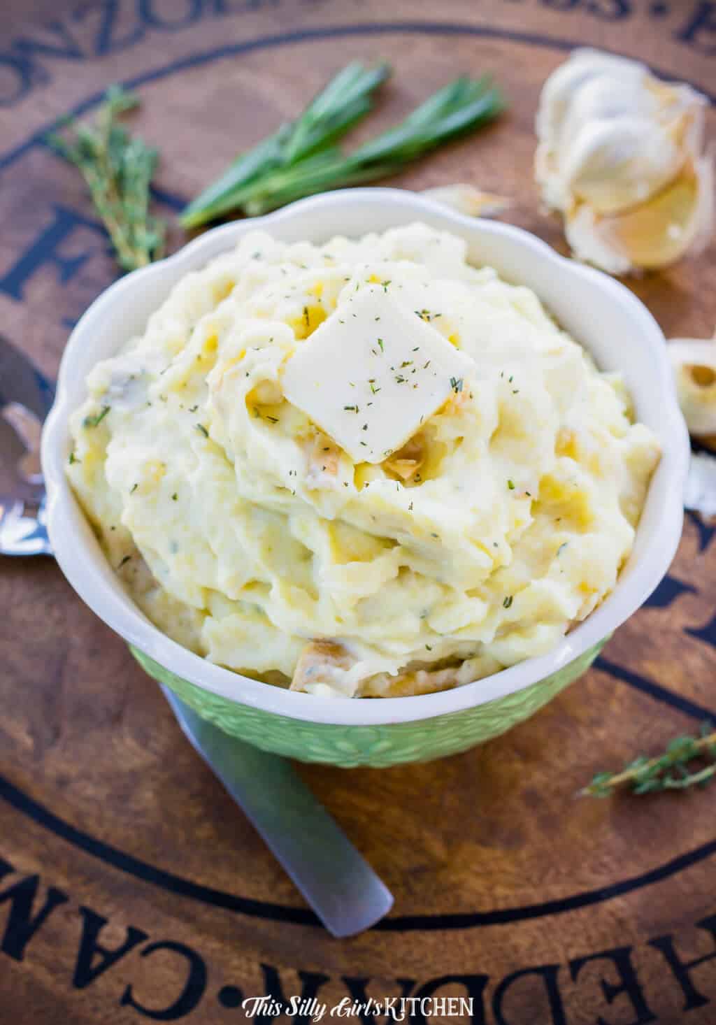 Green bowl full of Roasted Garlic Mashed Potatoes topped with butter