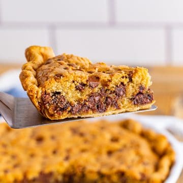 Pie server holding up slice of pie from pie plate.