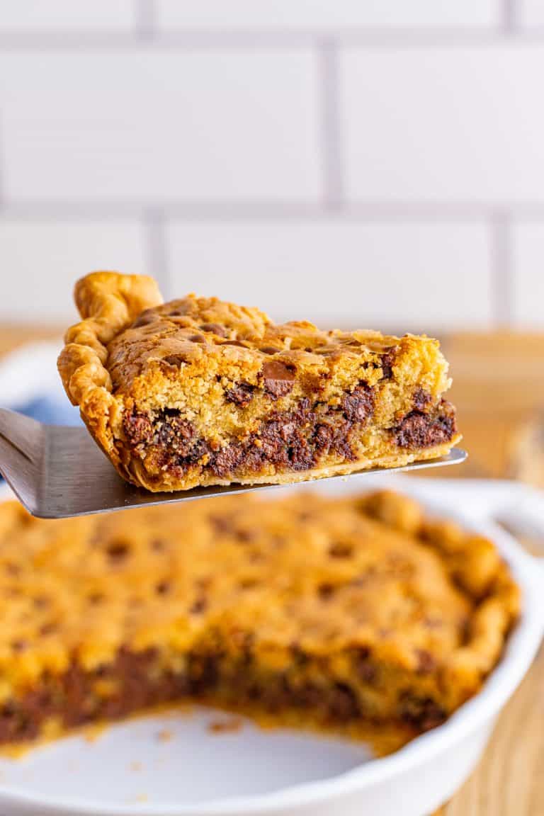 Pie server holding up slice of pie from pie plate.