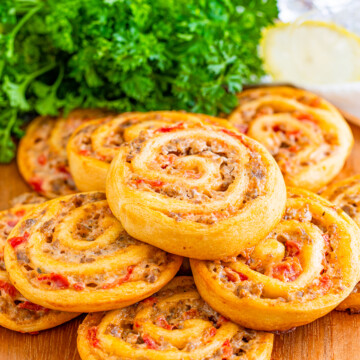 Stacked Sausage Dip Pinwheels on wooden platter.