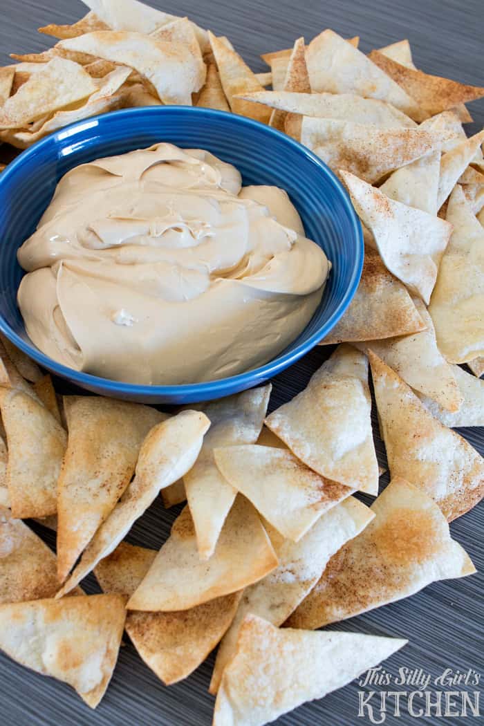 A blue bowl of creamy cookie butter dip surrounded by cinnamon sugar tortilla chips.