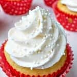 Valentine cupcakes topped with swirled vanilla bean buttercream and white pearl sprinkles in red polka dot liners.