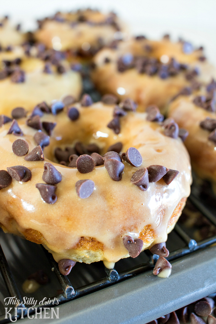 Baked Peanut Butter Banana Doughnuts, tender banana doughnuts dipped in peanut butter glaze and topped with mini chocolate chips! from ThisSillyGirlsLife.com