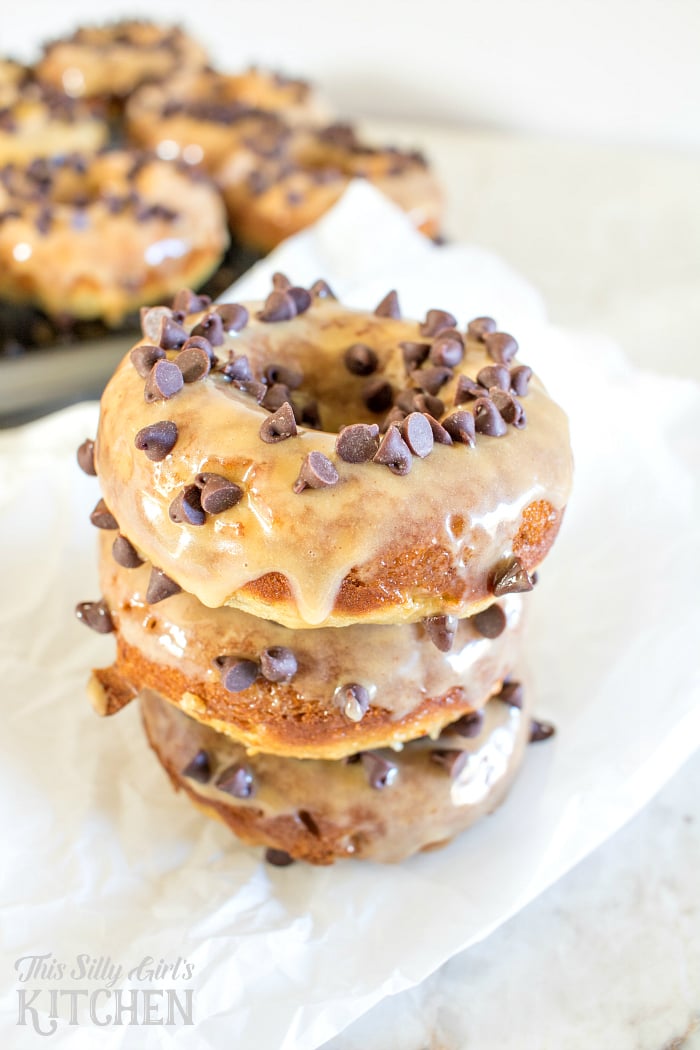 Baked Peanut Butter Banana Doughnuts, tender banana doughnuts dipped in peanut butter glaze and topped with mini chocolate chips! from ThisSillyGirlsLife.com