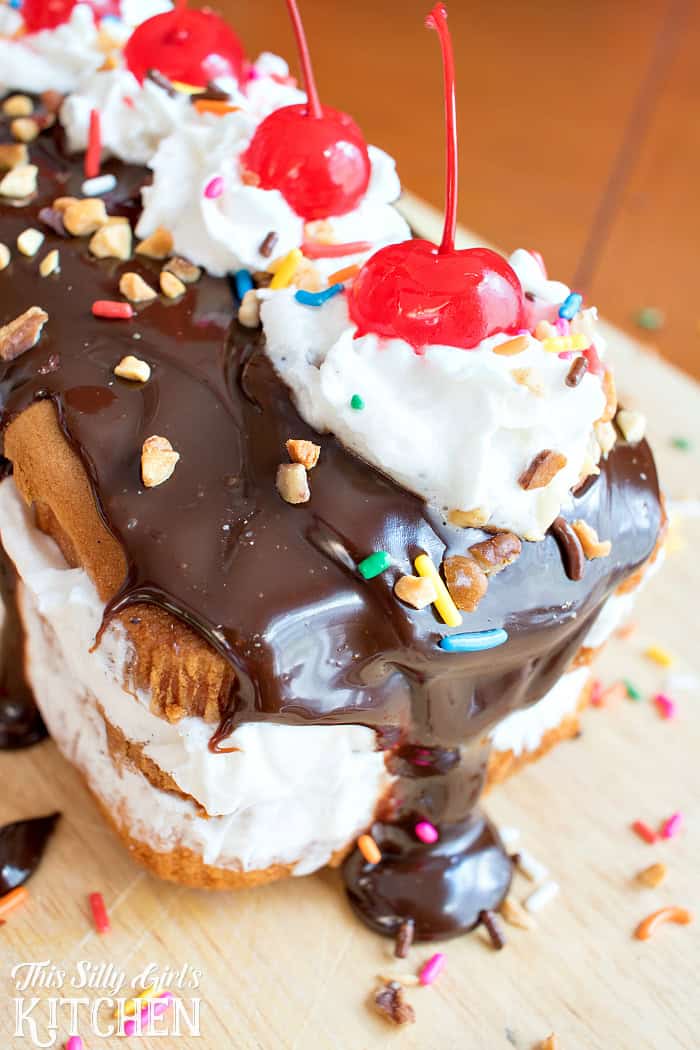 Finished hot fudge sundae cake topped with warm fudge, whipped cream, nuts, sprinkles, and cherries ready to slice.