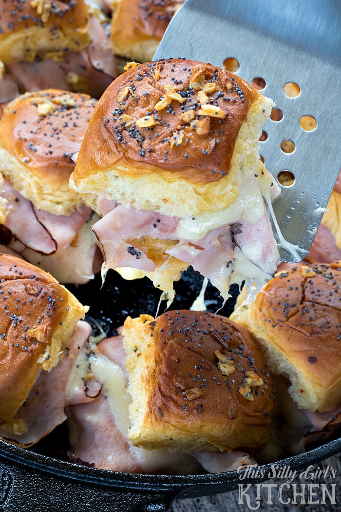 Cast Iron Baked Ham and Swiss Sliders lifted out of pan with spatula