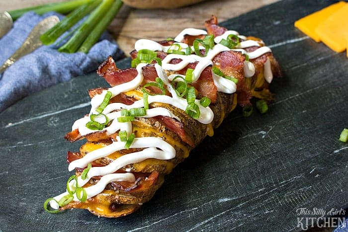 Close-up of a loaded hasselback potato with melty cheese and crispy bacon.