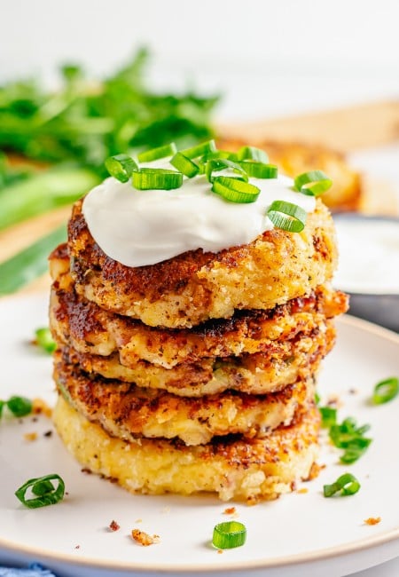 Square image of stacked cakes on white plate topped with sour cream and scallions.
