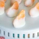 Frozen Yogurt Bites lined up on a white cake stand with clementine segments peeking from the yogurt.