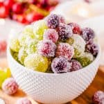 Candied Grapes in a small white bowl with sparkly sugar coating on a wooden cutting board.
