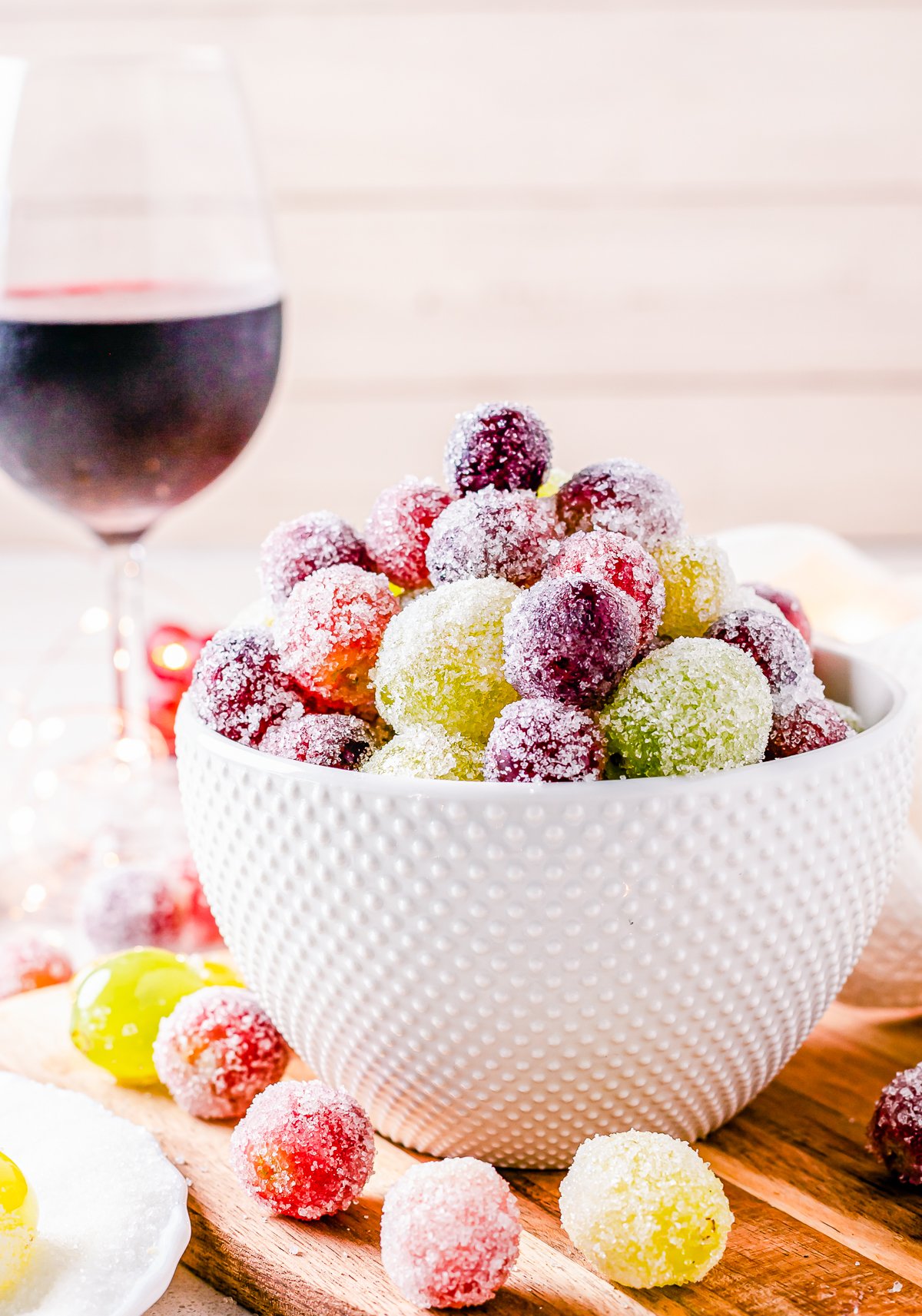 Side view of Candied Grapes with wine in background.