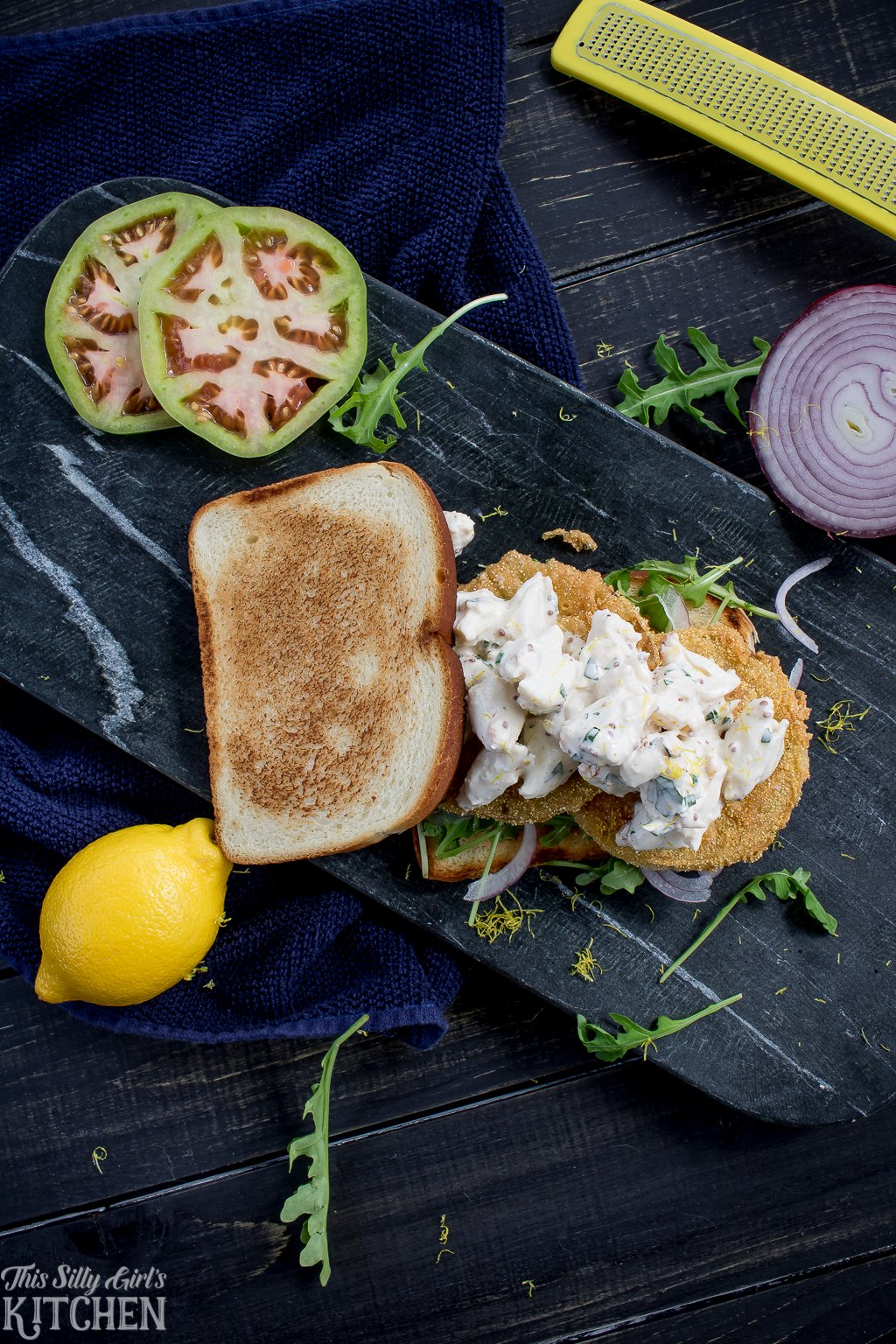 Fried Green Tomato Crab Salad Sandwiches, jumbo lump crab salad over fried green tomatoes, arugula and red onion, all between two slices of bread! Recipe from ThisSillyGirlsKitchen.com