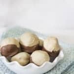 A bowl of peanut butter Oreo truffles dipped in a creamy coating with a chocolate bottom.