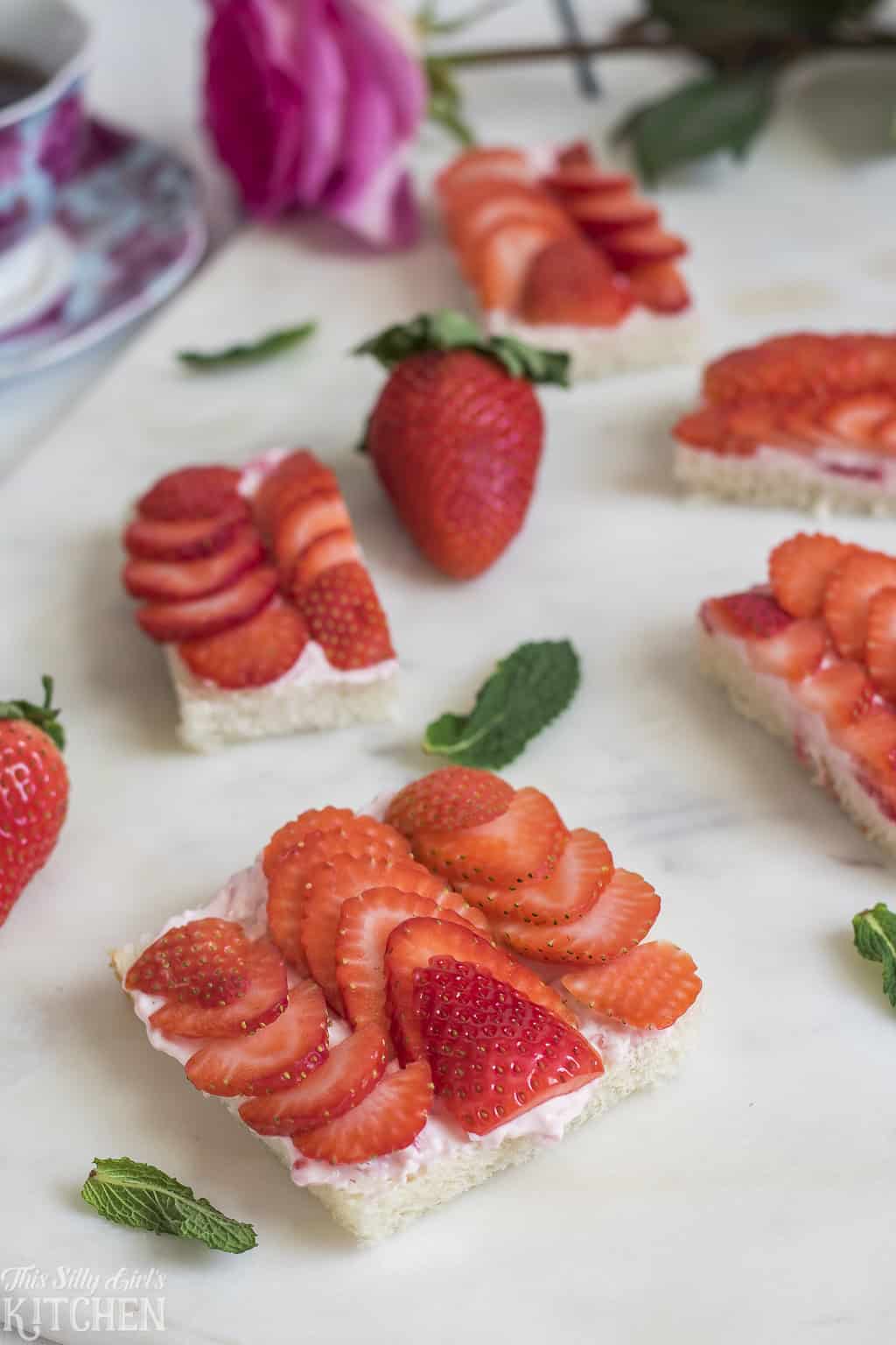 A close up of an open-faced strawberry tea sandwich with strawberry cream cheese and sliced berries.
