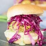 A lentil burger slider stacked with chimichurri yogurt sauce and dijon slaw on a slate board.