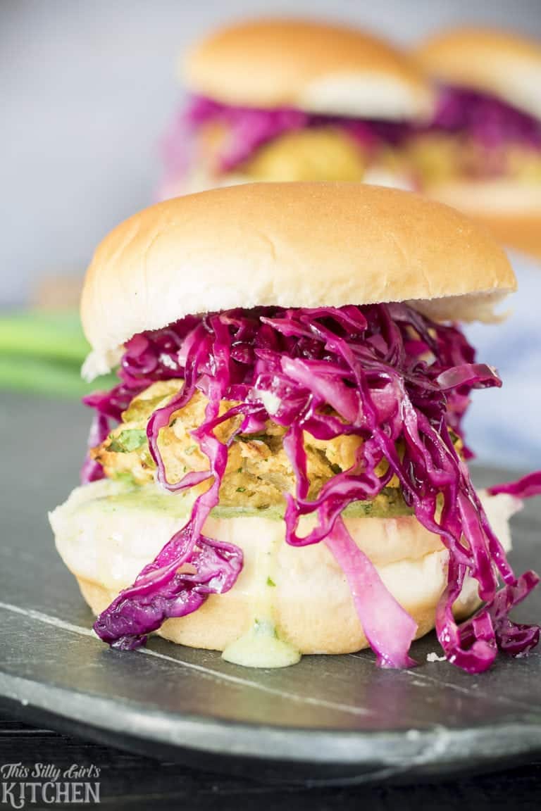 A lentil burger slider stacked with chimichurri yogurt sauce and dijon slaw on a slate board.