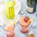 Two glasses of strawberry limoncello slush with a limoncello bottle and sparkling wine.