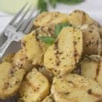 Close up of Grilled Potato Salad showing grill marks on tender potatoes in a pesto Dijon dressing.