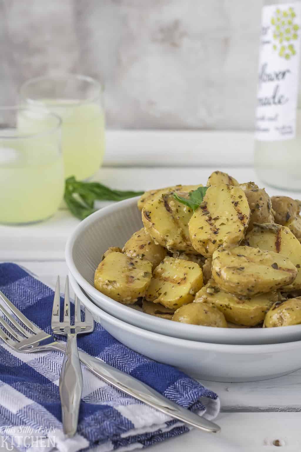 Warm Grilled Potato Salad in a serving bowl with a blue checked napkin.