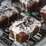 A mini oreo banana bread loaf on a cooling rack topped with cookies and cream glaze.
