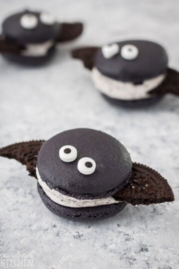 Halloween Macarons decorated as bats with chocolate cookie wings and candy eyes.