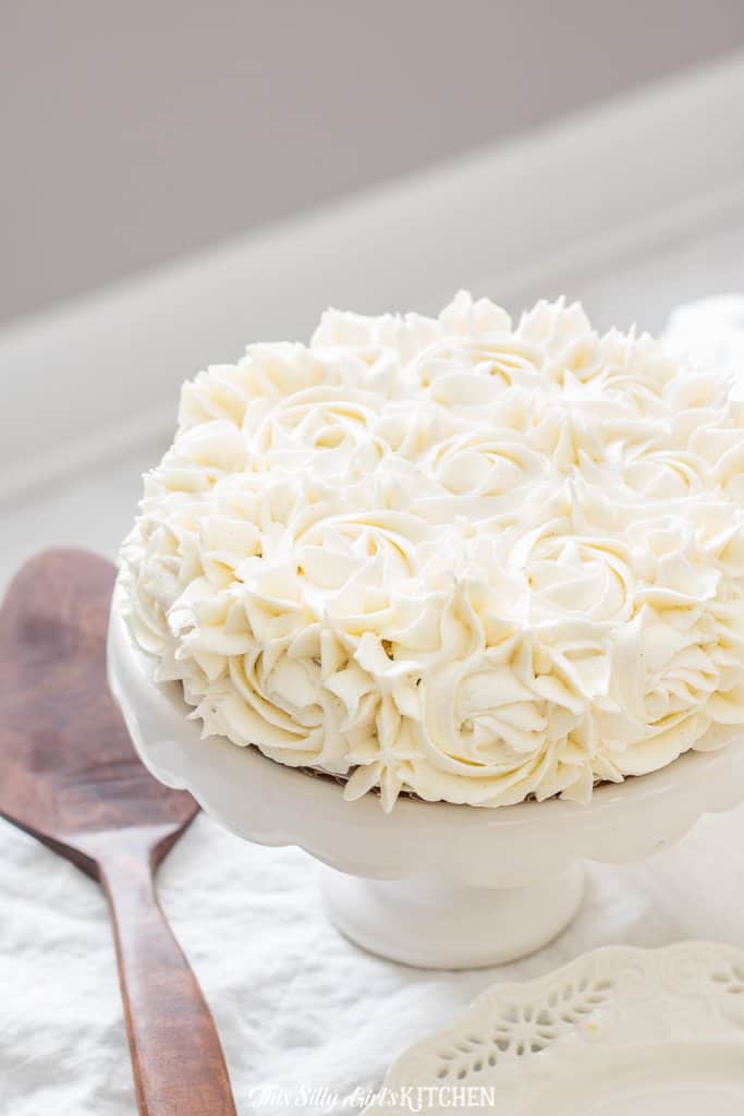 Buttercream Frosting piped onto a cake on white cake stand.