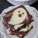 A stack of cheesecake brownies on a white plate showing the fudgy brownie and creamy cheesecake layers.