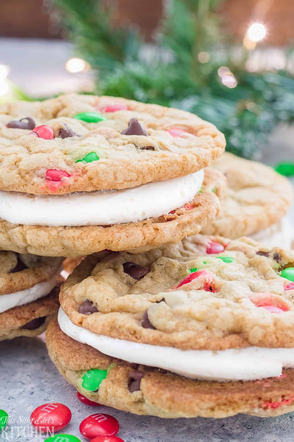 Christmas Cookie Sandwiches, the fluffiest buttercream frosting sandwiched between two soft and chewy chocolate chip cookies loaded with holiday M&M's! #Recipe from ThisSillyGirlsKitchen.com #ChristmasCookies #SandwichCookies #CookiesForSanta #Christmas