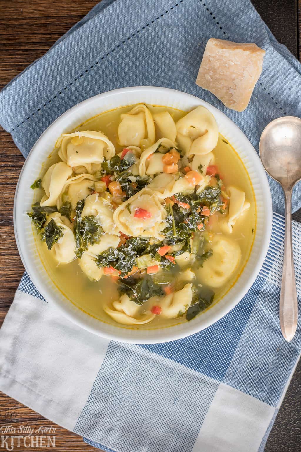 Bowl of Tortellini Soup overhead with spoon and blue and white linens