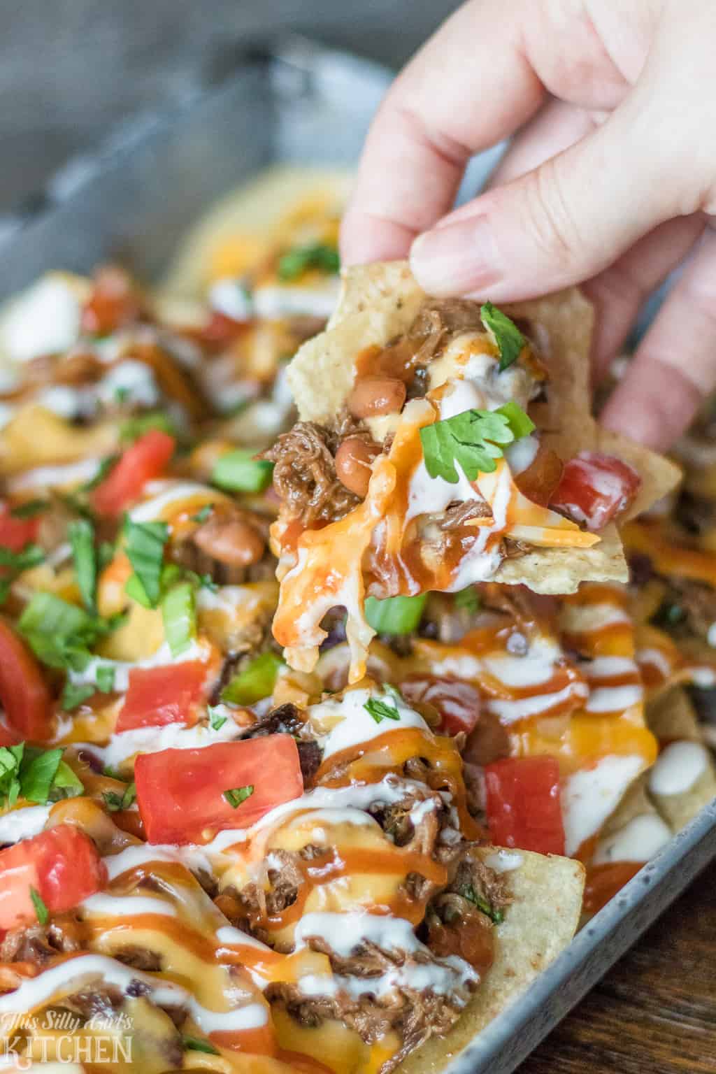 #BBQ Beef #Nachos, layered nachos piled high with tender beef, cheese sauce, and all the fixins! #Recipe from ThisSillyGirlsKitchen.com #bbqbeef #appetizer