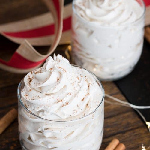 Bowl of Stabilized Whipped Cream with Cornstarch piped into a soft white cloud on a wooden surface.