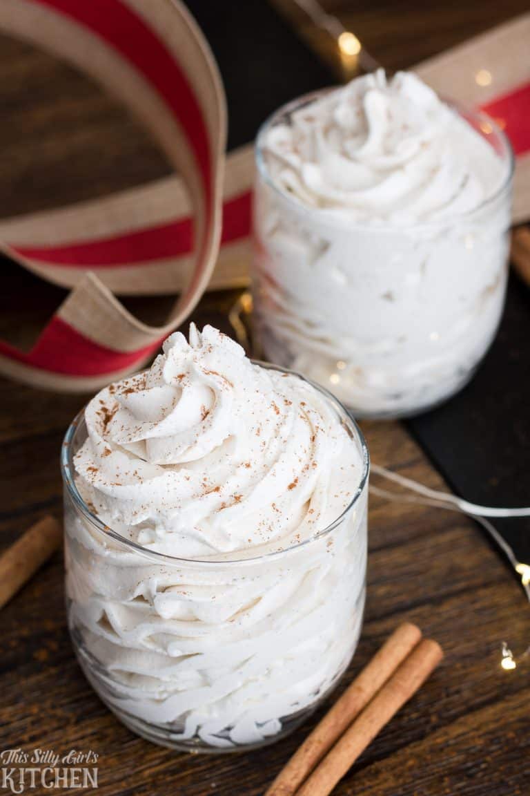 Bowl of Stabilized Whipped Cream with Cornstarch piped into a soft white cloud on a wooden surface.