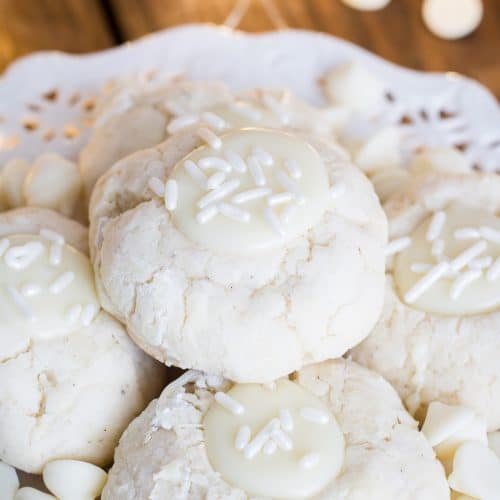 A plate of soft white chocolate Thumbprint Cookies filled with white ganache and sprinkles.
