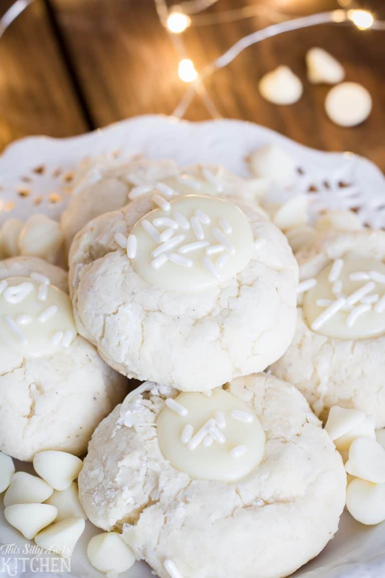 A plate of soft white chocolate Thumbprint Cookies filled with white ganache and sprinkles.