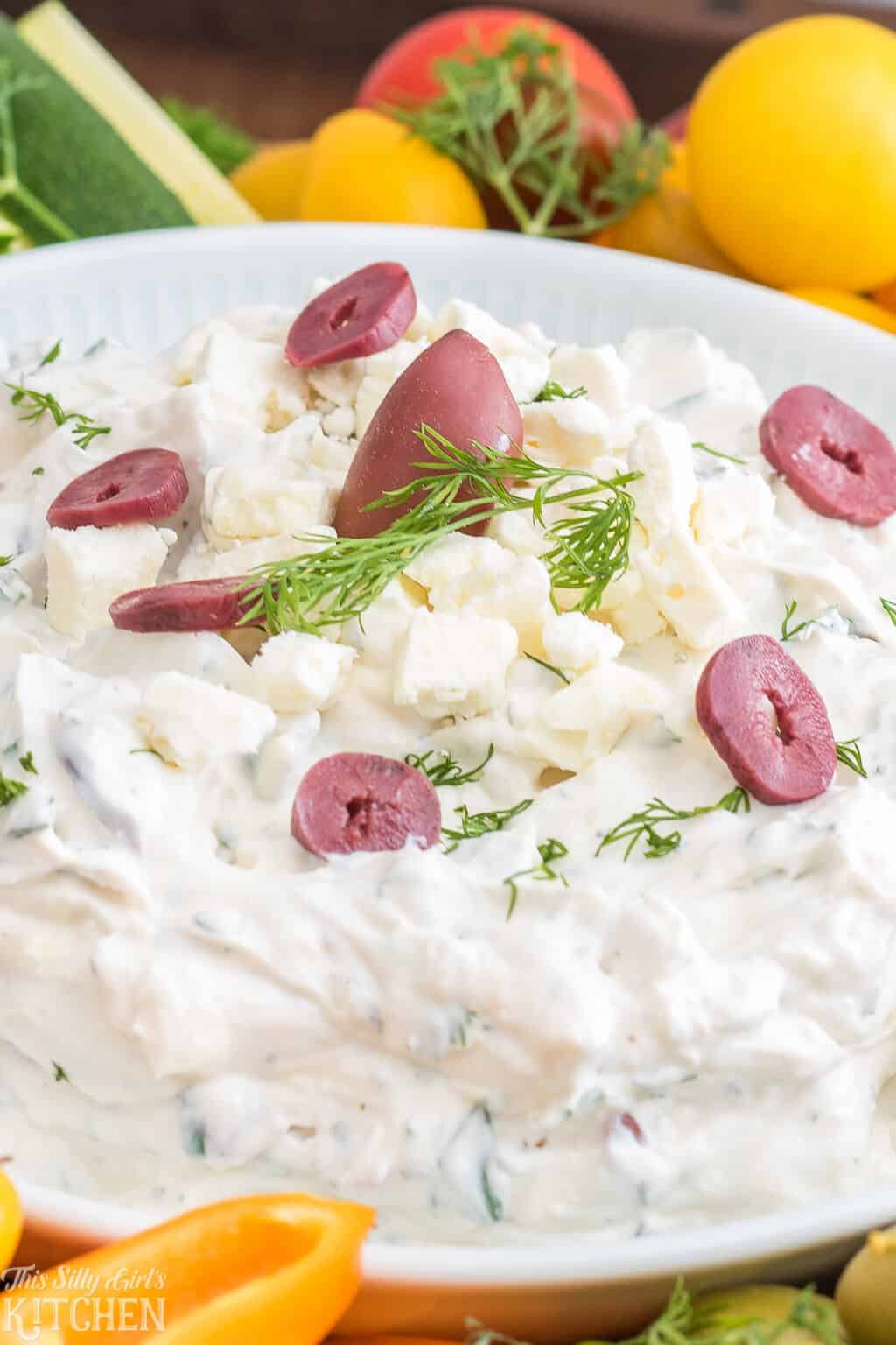 Close up of dip topped with olives and dill