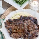 Best Ribeye Marinade Recipe finished on the grill, sliced and resting on a wooden cutting board.