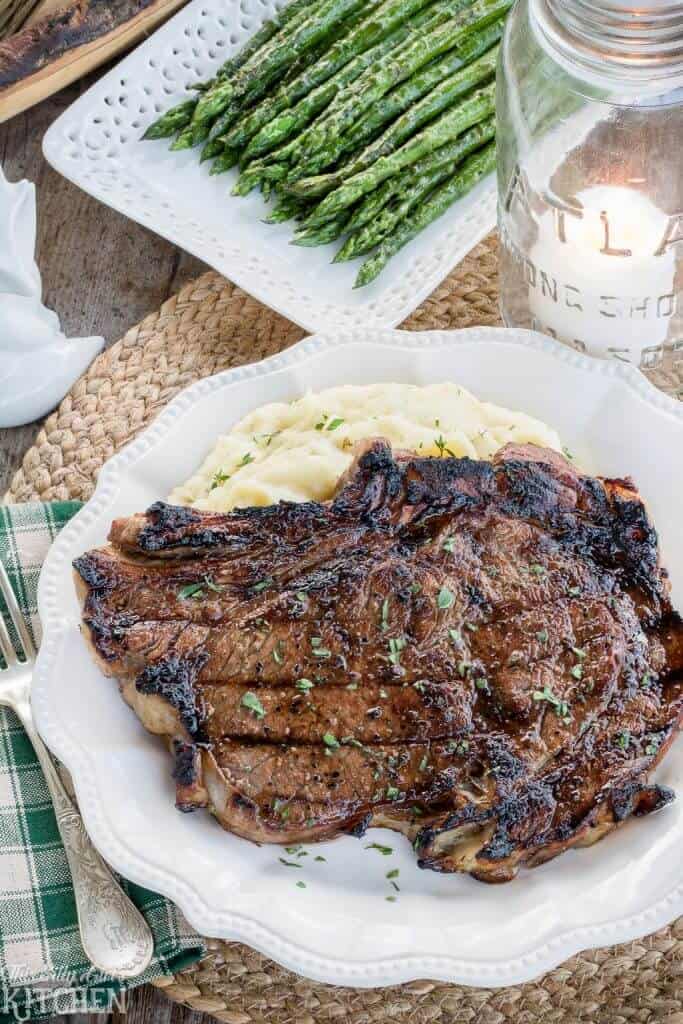 Best Ribeye Marinade Recipe finished on the grill, sliced and resting on a wooden cutting board.