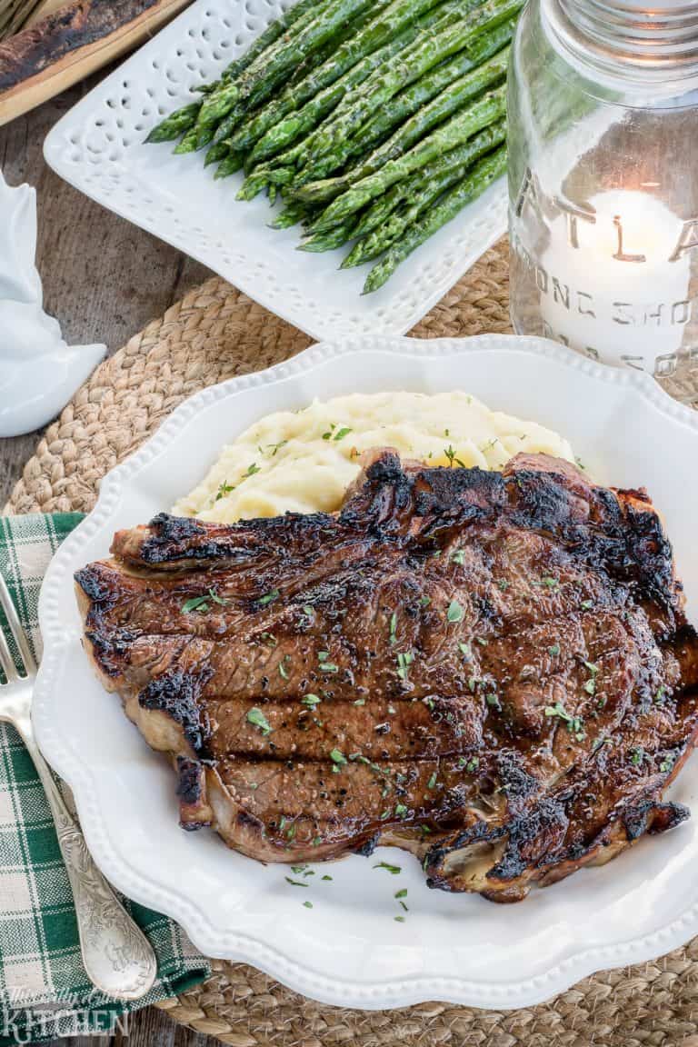 Best Ribeye Marinade Recipe finished on the grill, sliced and resting on a wooden cutting board.