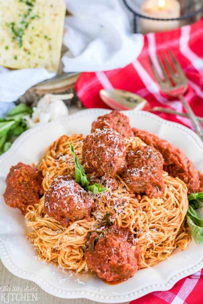 Spaghetti and Meatballs piled on white plate garnished with basil
